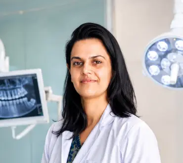 Dr. Nidhi Singh, experienced Indian female dentist standing in a modern dental clinic with advanced dental equipment