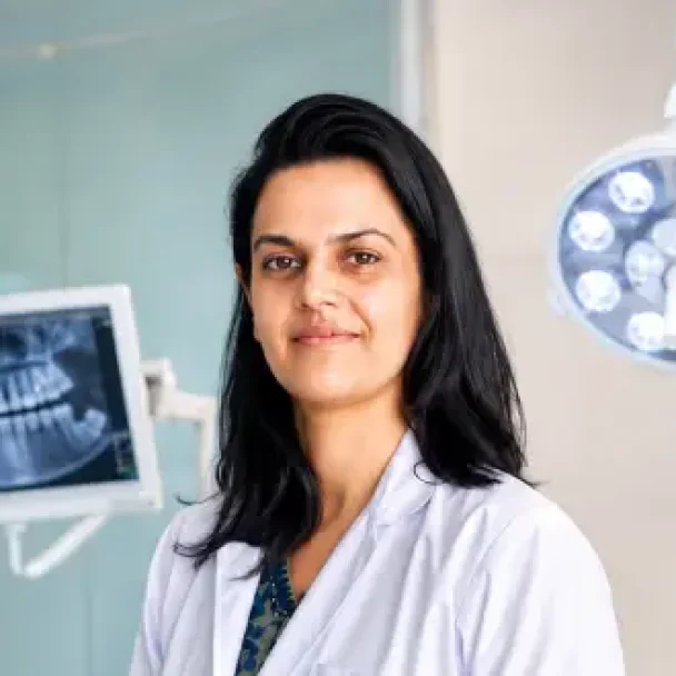 Dr. Nidhi Singh, experienced Indian female dentist standing in a modern dental clinic with advanced dental equipment